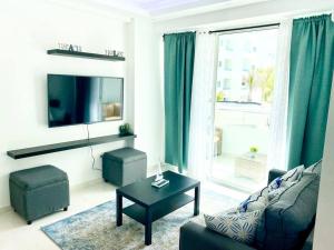 a living room with a couch and a table and a tv at Beautiful and peaceful 2-bedroom family condo in Juan Dolio