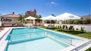 a swimming pool with chairs and umbrellas in a yard at Calma Living in Potos