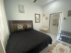 a bedroom with a black bed and two chairs at Maison Helysa Homestay in Lumut +55 photos