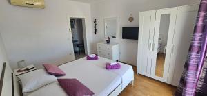 a bedroom with a white bed with purple pillows at Apartmani Pavla in Orebić
