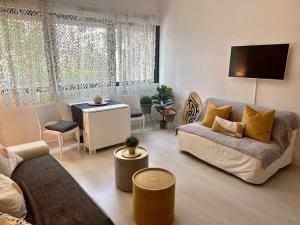 a living room with a couch and a table at Spacieux studio Arcachon centre "5 nuits minimum" Parking gratuit in Arcachon