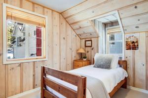 een slaapkamer met houten wanden, een bed en 2 ramen bij Alpine Cottage Hideaway in Stateline