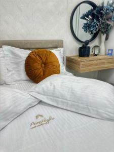 a white bed with a brown pillow on it at Psimithefto Luxury Apartments in Thessaloniki
