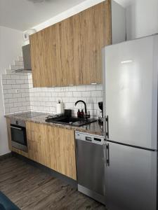 Una cocina con gabinetes de madera y un refrigerador de acero inoxidable. en Modern Studio in Old Town, en Poznan 1 foto más