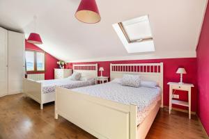 two beds in a bedroom with pink walls at Casa Los Mozos, a 9 kilómetros de Santander y a 6 de Cabárceno in El Astillero