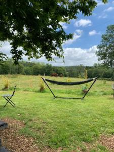 eine Hängematte auf einem Feld mit Pferden im Hintergrund in der Unterkunft American School Bus Retreat with Hot Tub in Sussex Meadow in Uckfield