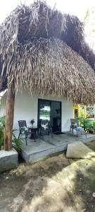 a large straw hut with two chairs and a table at Chagres River Lodge in Santa Rosa
