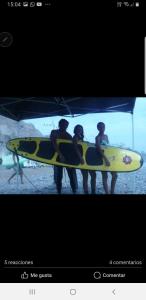 a group of three people holding a yellow surfboard at Huanchaco Surf Camp in Huanchaco