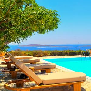 a row of picnic tables next to a swimming pool at Paros Afrodite Luxury Villas in Aliki
