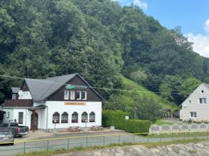 a building on the side of a road with a mountain at Penzion a Rybářská bašta U Jesetera in Jeseník