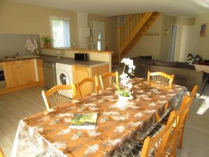 a dining room table with chairs and a kitchen at Gîte de la chouette in Hattenville