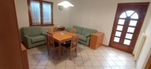 a living room with a table and chairs and a door at Residenza Al Capitello in Ceniga