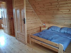 a bed in a room with a wooden wall at Domek Arkadia in Gąski
