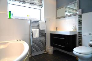 a bathroom with a tub and a sink and a toilet at Sleeps 10, Free parking, close to Science Park, King size bed in Milton +57 photos