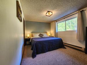 una camera da letto con un letto con un copriletto blu e una finestra di Crescent Beach Retreat- Cozy 4br House a Port Angeles
