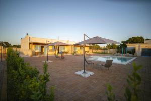 un patio con sillas y sombrillas junto a una piscina en Dimore degli Ulivi, en Leporano