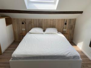 a bedroom with a bed with white sheets and a window at Duplex in Waimes