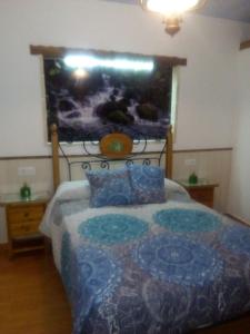 a bedroom with a bed with a picture on the wall at Casa Rural Majaceite in El Bosque
