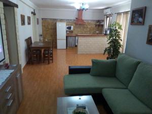 a living room with a green couch and a kitchen at Casa Rural Majaceite in El Bosque