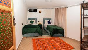 una camera da letto con due letti con lenzuola verdi e un tappeto di Appart Sahraoui Medina a Fès al Bali