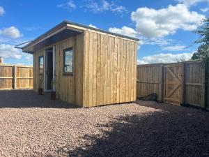 a wooden shed with a fence in a yard at Maylands Farm Glamping Pod in Hilperton