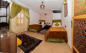 una camera d'albergo con due letti e una tv di Appart Sahraoui Medina a Fès al Bali