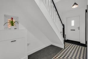 a hallway with white walls and a staircase with a potted plant at Stanley Park House Peterborough - 3 bed, 3 bathroom, parking, garden in Peterborough