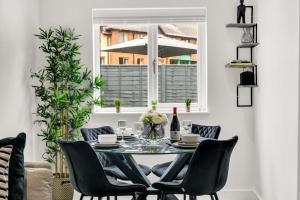 a dining room table with black chairs and a window at Stanley Park House Peterborough - 3 bed, 3 bathroom, parking, garden in Peterborough