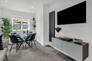 a dining room with a table and a tv on a wall at Stanley Park House Peterborough - 3 bed, 3 bathroom, parking, garden in Peterborough