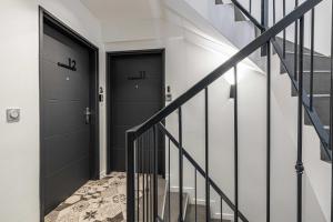 un couloir avec deux portes noires et un escalier dans l'établissement Résidence du Vieux-Port Cannes, à Cannes