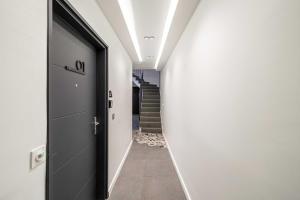 un couloir avec une porte noire et un escalier dans l'établissement Résidence du Vieux-Port Cannes, à Cannes