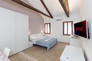 une chambre avec un lit et une télévision sur un mur dans l'établissement Accogliente Monolocale Veneziano2 Aria Condizionata, vicino a campus e stazione, à Venise