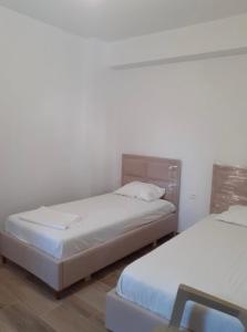 two beds in a room with white walls at La casa de Alex in Sarandë