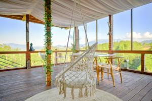 a hammock on a deck with a table and chairs at Panoramic Paradise Estate - Sauna & Pool in Zărneşti