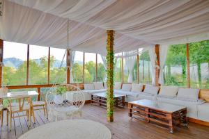 a living room with white couches and tables and windows at Panoramic Paradise Estate - Sauna & Pool in Zărneşti