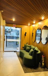 a living room with a green couch and mirrors at Apartamento Mar grosso 100 metros do MAR in Laguna