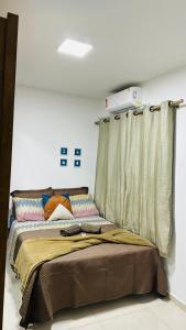 a bed in a white room with a curtain at Apartamento Mar grosso 100 metros do MAR in Laguna