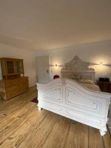 a large white bed in a room with wooden floors at Schlosstaverne Sighartstein Familienzimmer in Neumarkt am Wallersee +5 photos