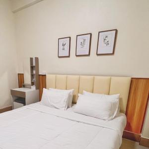 a bedroom with a large white bed with three pictures on the wall at The Betong Life Guesthouse in Betong