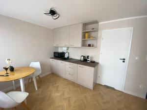 a kitchen with white cabinets and a table and a door at Apartamenty W NIEBIE in Słupsk