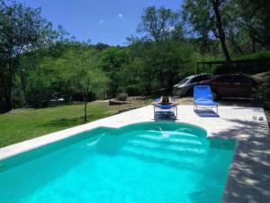 a swimming pool with two chairs and a person sitting in them at Cabaña La Cotita in Villa Los Aromos