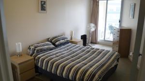 a bedroom with a bed with a striped comforter and a window at City Plaza in Canberra