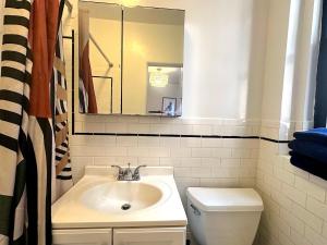 a bathroom with a sink and a toilet and a mirror at West Village Lush Green in New York