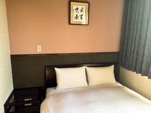 a bed with two pillows and a picture above it at Rinn Hostel Miyagawacho in Kyoto