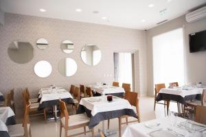a restaurant with white tables and chairs and mirrors at FAIAS - Boutique Hotel in Luanda
