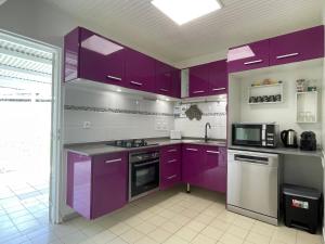 a kitchen with purple cabinets and a microwave at Villa Caraïbes in Sainte-Luce