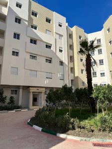 a large building with a palm tree in front of it at Appartement Tanger in Tangier