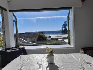a table with glasses and a vase of flowers on it at Lake Rotoiti Lakehouse Retreat in Rotorua