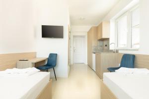two beds in a room with a desk and a kitchen at Millennia Hotel in Sofia