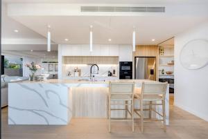 a kitchen with a island with chairs and a sink at The Hamptons Lake House - Noosa Heads Luxury House in Noosa Heads